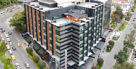 Se ve un edificio desde un plano aéreo, a lado y lado se ven las calles con vehículos que transitan.