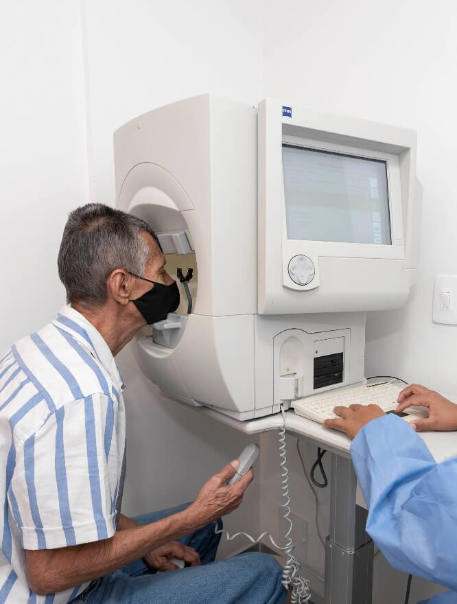 Se ve a un paciente con la cara en un equipo médico que se infiere tiene como fin revisar sus ojos. 